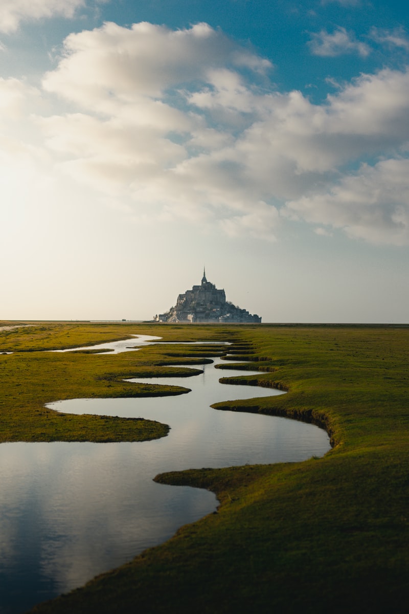 photo of grass field and spiral lake and gray castle scenery