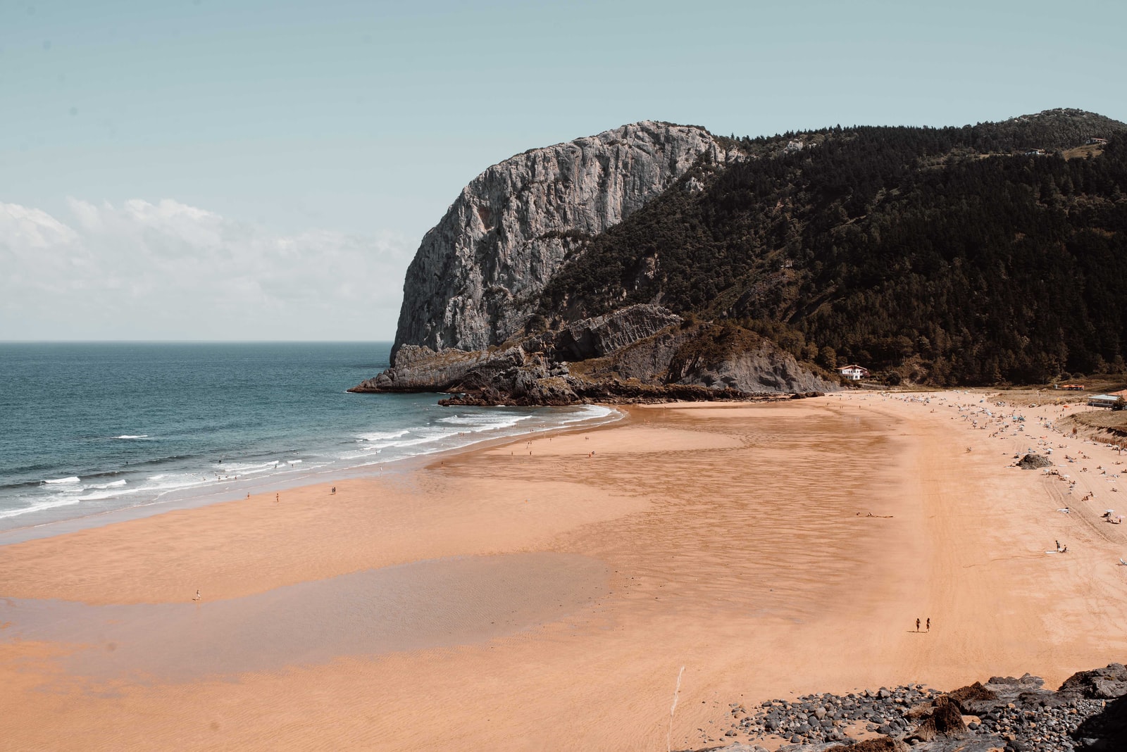 brown sand beach near brown rocky mountain under blue sky during daytime