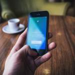 person holding turned on space gray iPhone 5c near table