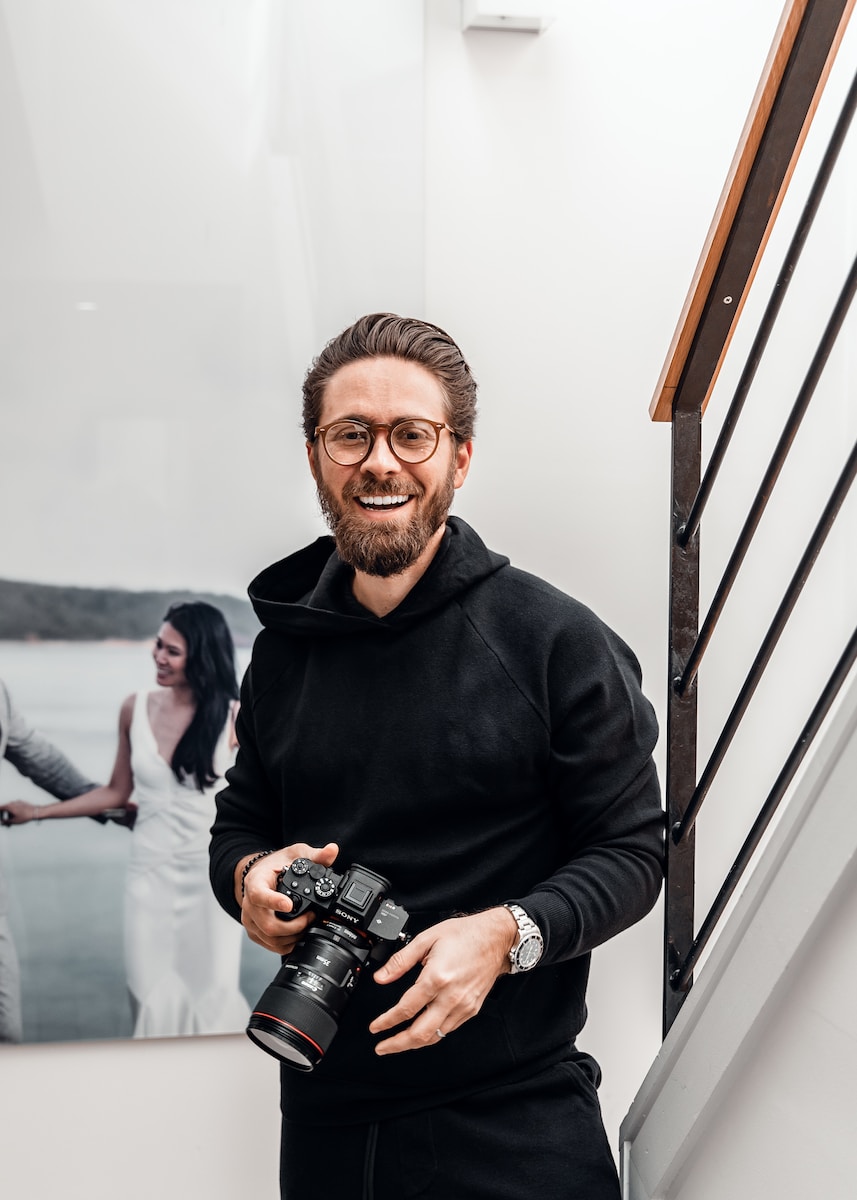 man in black sweater holding black dslr camera