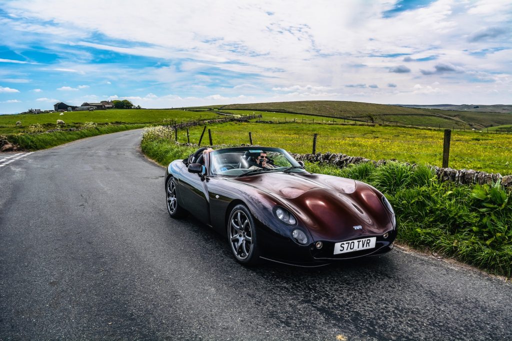 red convertible coupe parking near road under white and blue sky