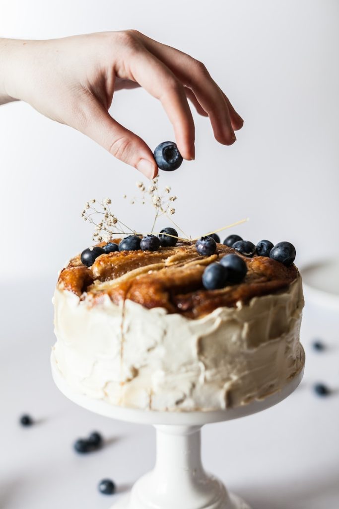 8 astuces pour maîtriser l’art de la pâtisserie française person holding black fruit near cake