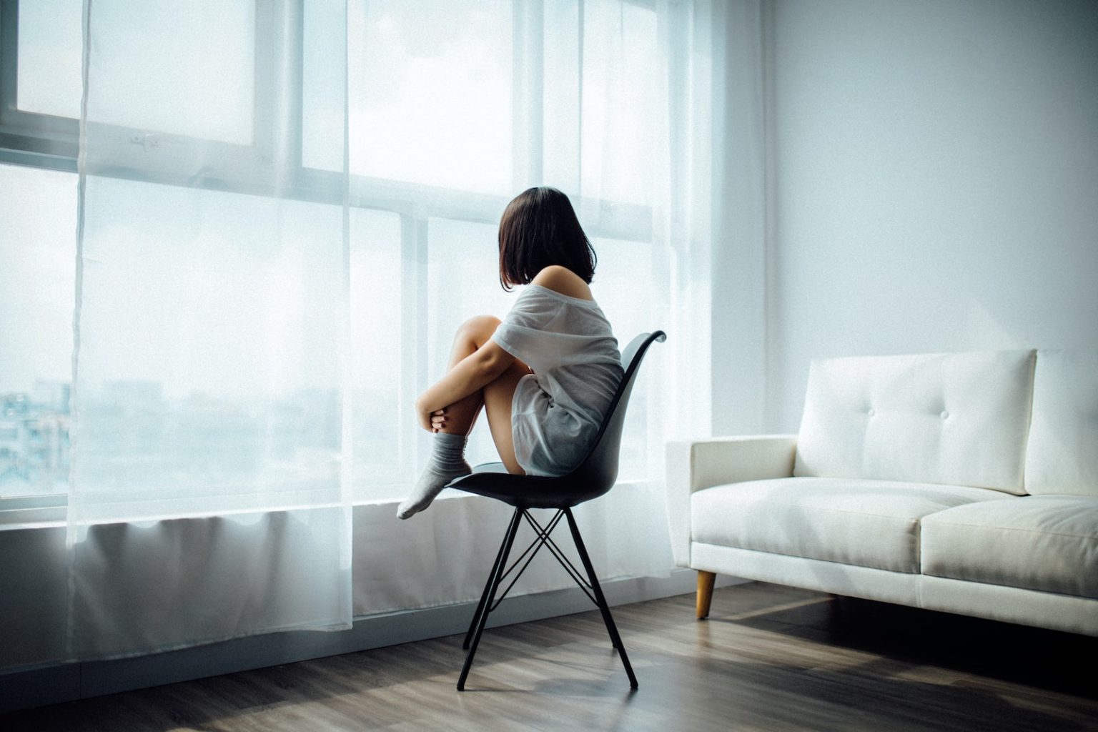 7 conseils pour prendre soin de votre santé mentale au quotidien woman sitting on black chair in front of glass-panel window with white curtains