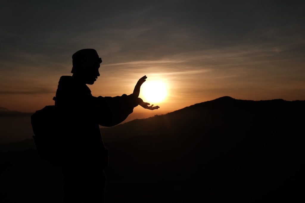 silhouette of man standing on top of mountain during sunset