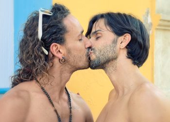 two men with long hair are kissing each other
