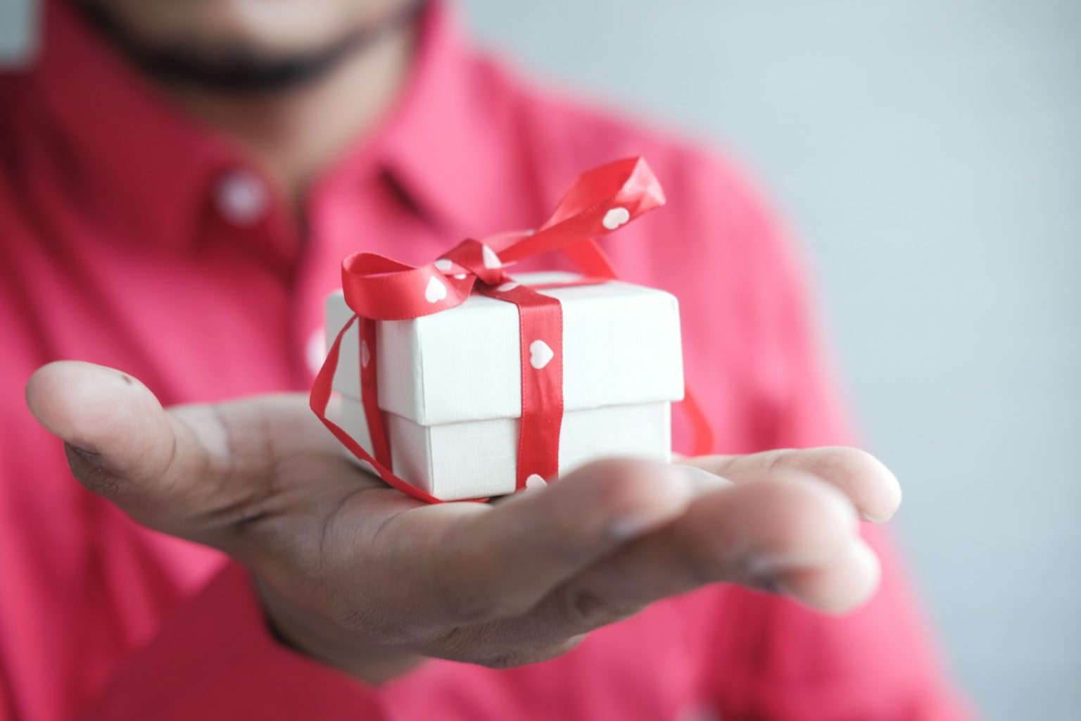 Les meilleures idées cadeaux pour une amie qui part à l’étranger a man holding a white gift box with a red ribbon